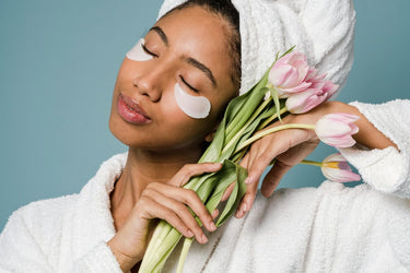 woman wearing under eye patches and holding a bunch of tulips