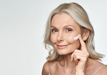 Smiling middle-aged lady applying face cream