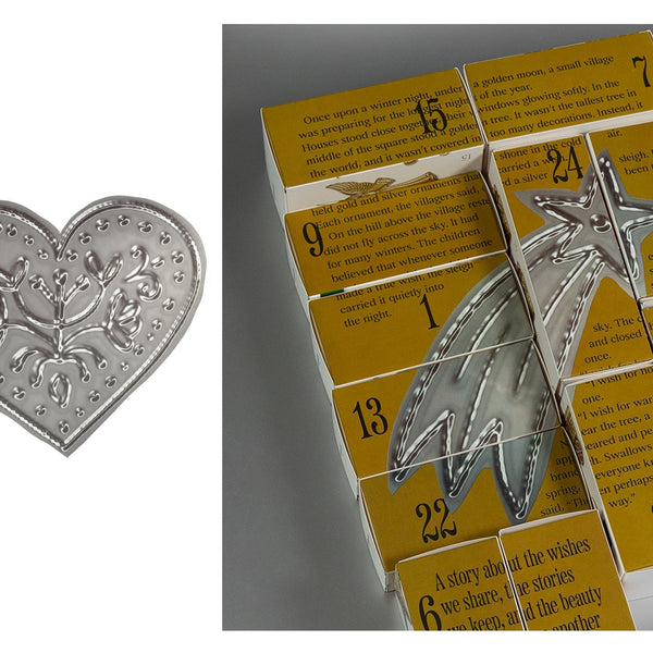 Silver-toned metal bookmarks shaped like a heart and a star, displayed alongside yellow booklets with printed text and numbers.