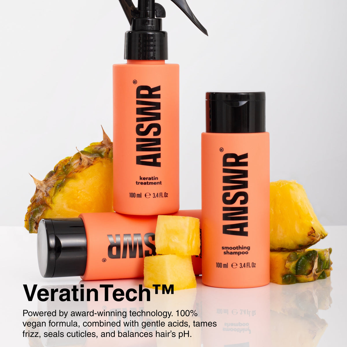 Orange shampoo bottles with black caps on a white background, surrounded by pineapple slices.
