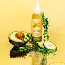 Hair spray bottle with avocado, cucumber, and rosemary on a yellow background