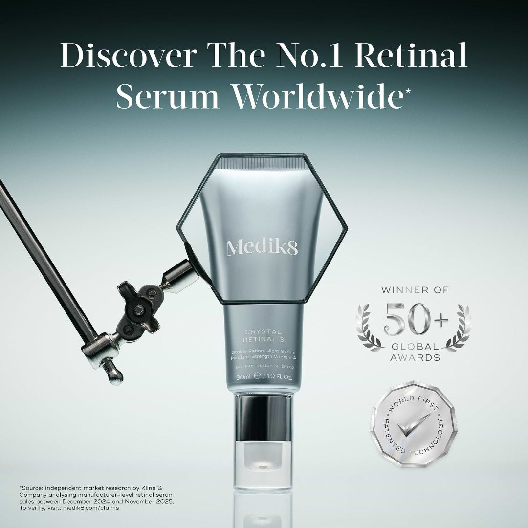 Medik8 Crystal Retinal 3 serum bottle shown on a gradient gray background with promotional text and award badges. A light stand is visible at left, and the bottle is centered with a reflective base.