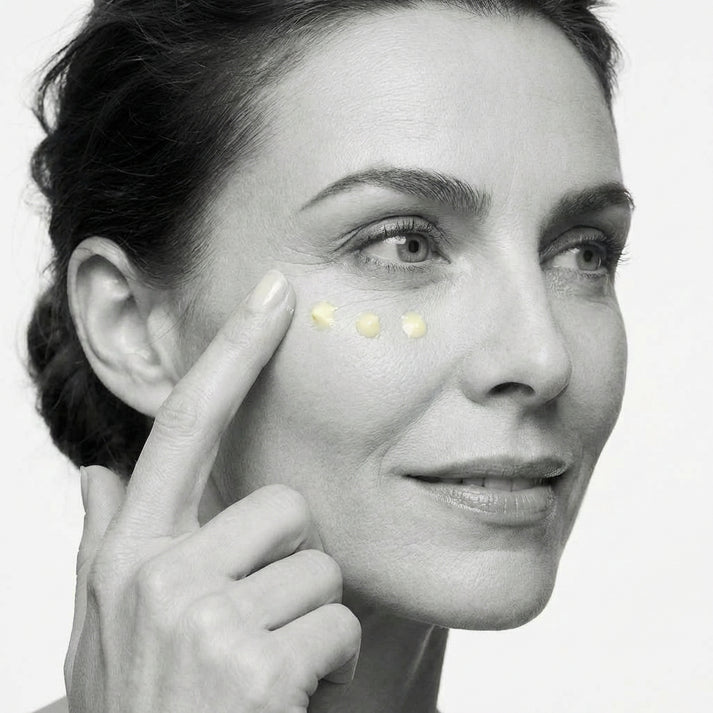 Woman applying cream to her face with a close-up of her eye area.