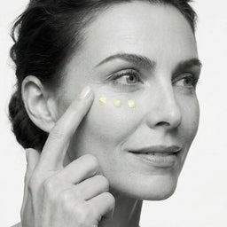 Woman applying cream to her face with a close-up of her eye area.