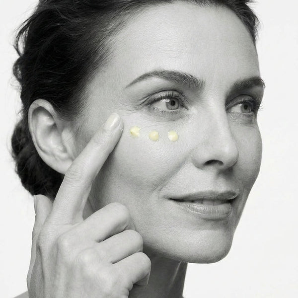Woman applying cream to her face with a close-up of her eye area.