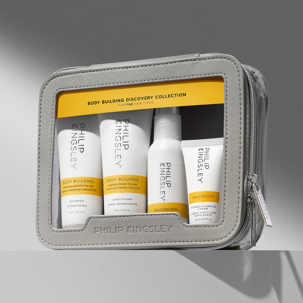 Philip Kingsley Body Building Discovery Collection travel set in a gray zippered pouch, containing four white and yellow shampoo, conditioner, body butter, and treatment bottles.