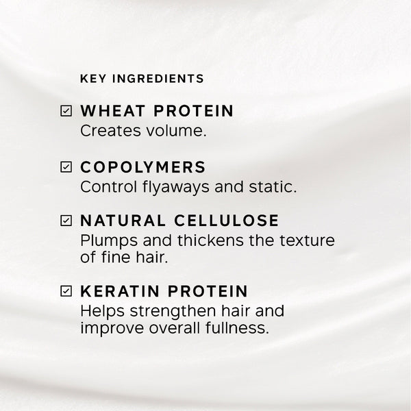A close-up of a white or very light beige fabric background with black text listing key ingredients: wheat protein, copolymers, natural cellulose, and keratin protein, each with a checkmark.