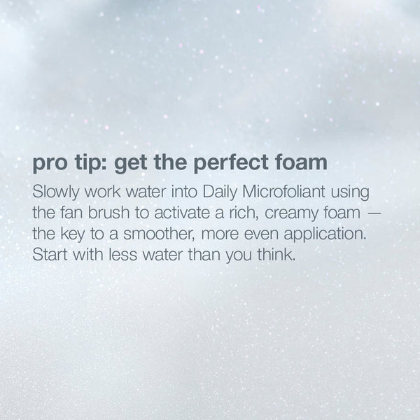 A text-based beauty tip graphic on a soft white and light gray background with faint speckled texture. The text reads: 'pro tip: get the perfect foam' followed by instructions about mixing water into Daily Microfoliant with a fan brush to activate rich, creamy foam.