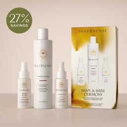 Four white Innersense hair care bottles and a gold-and-white product box are arranged on a beige studio background, with a green circular badge in the upper left reading '27% SAVINGS'. Visible brand text on the products and box is INNERSENSE.