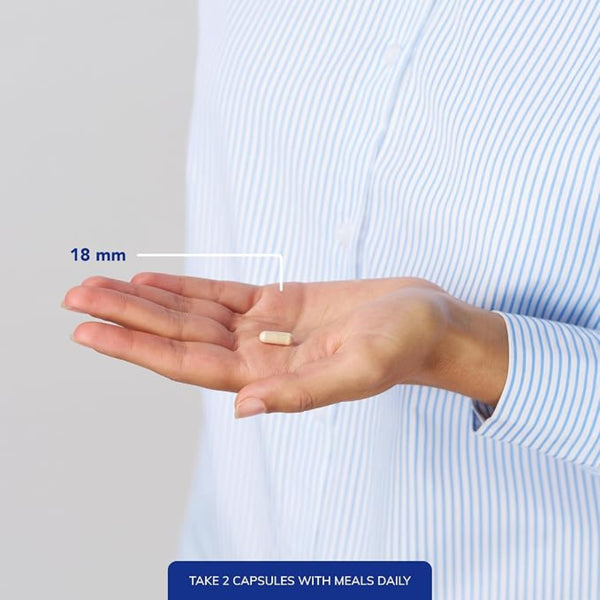 Hand holding a capsule with measurement label and text on a plain background