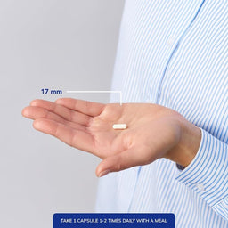 Hand holding a capsule with measurement label and text on a plain background