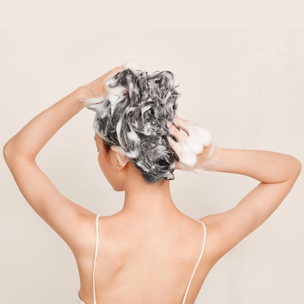 Person with shampoo on their head against a beige background