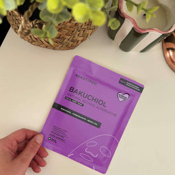 Purple facial sheet mask package with 'BeautyPro' branding held by a hand on a white surface.