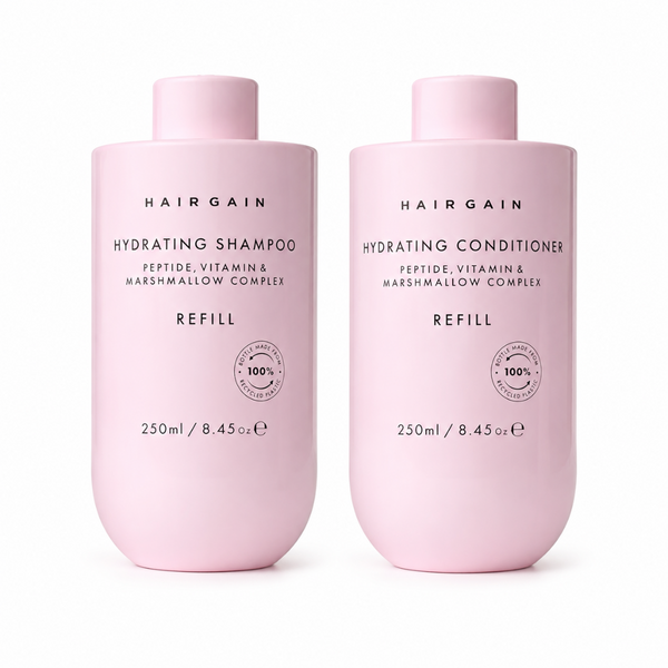Two light pink Hairgain haircare bottles on a white background: Hydrating Shampoo and Hydrating Conditioner, both labeled REFILL and 250ml.