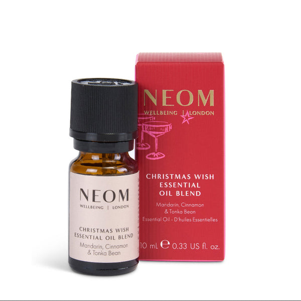 NEOM Christmas Wish Essential Oil Blend in a 10 mL amber glass bottle with a black cap, shown next to its red packaging box on a white background.