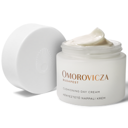 Omorovicza Cushioning Day Cream in a white jar with its lid off, showing a dollop of the cream on top, on a white background.