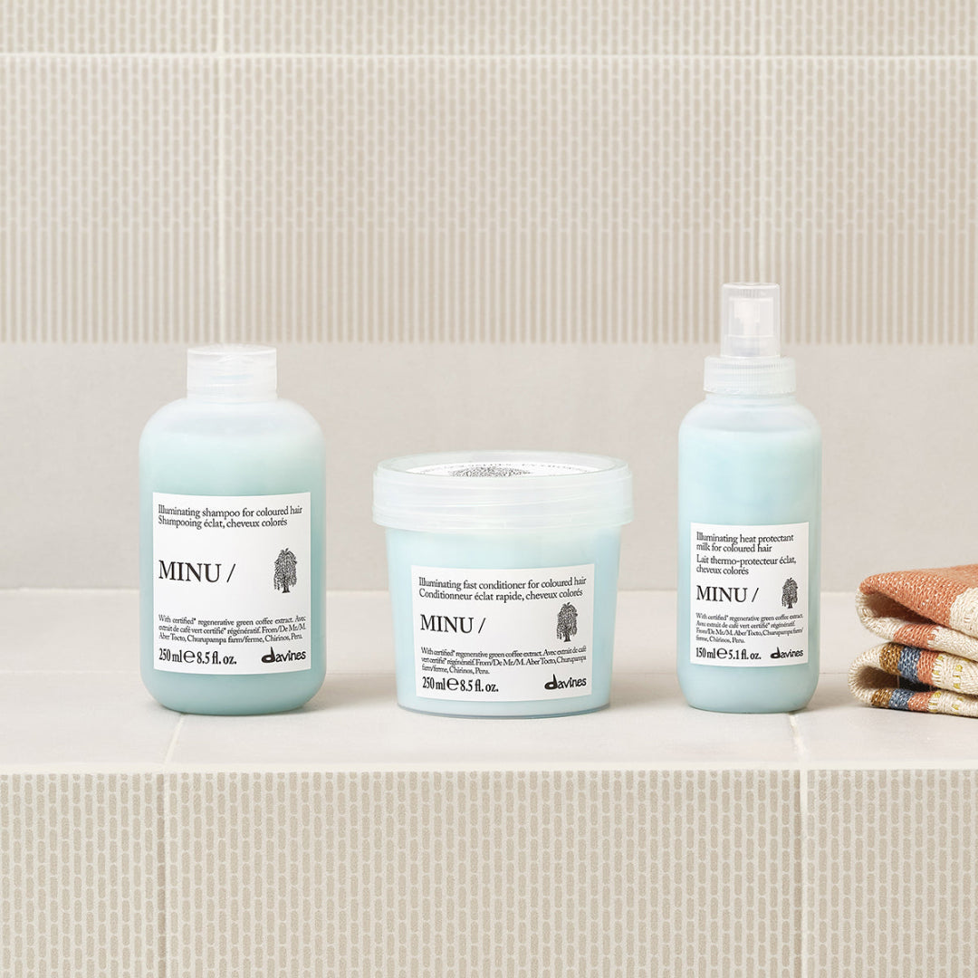 Three Davines hair care products on a bathroom counter with a tiled wall background.