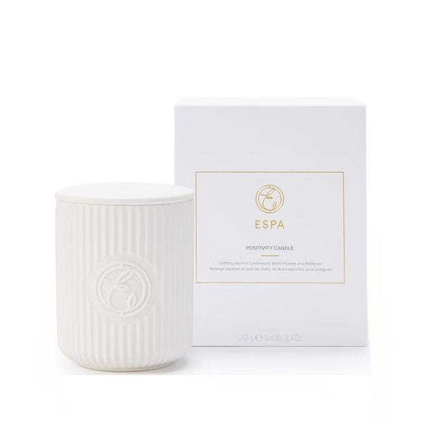 White candle with ribbed texture next to its packaging box on a white background