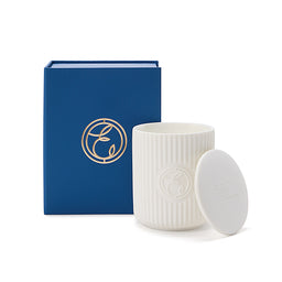 White ribbed candle with lid and blue box featuring a logo on a white background