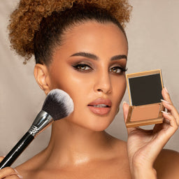 a woman using a Sigma Beauty F78 Ultimate Bronze to apply makeup