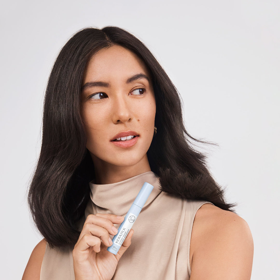 Woman holding a blue and white cosmetic product against a plain background