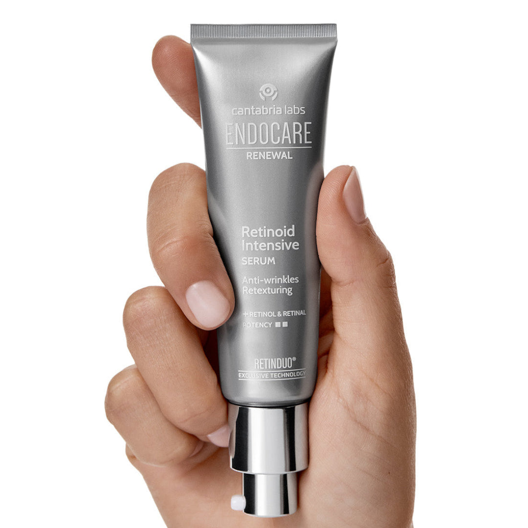 Hand holding a silver tube of Endocare skincare product on a white background
