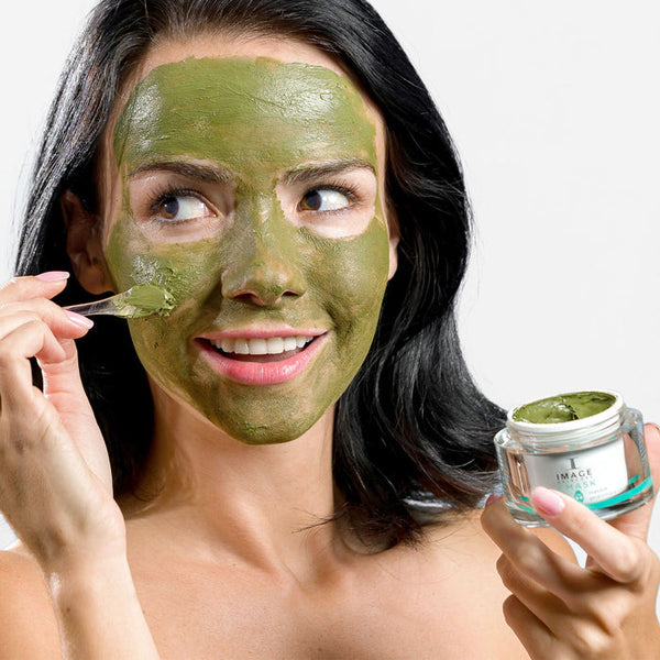 a model applying the green mask to her face