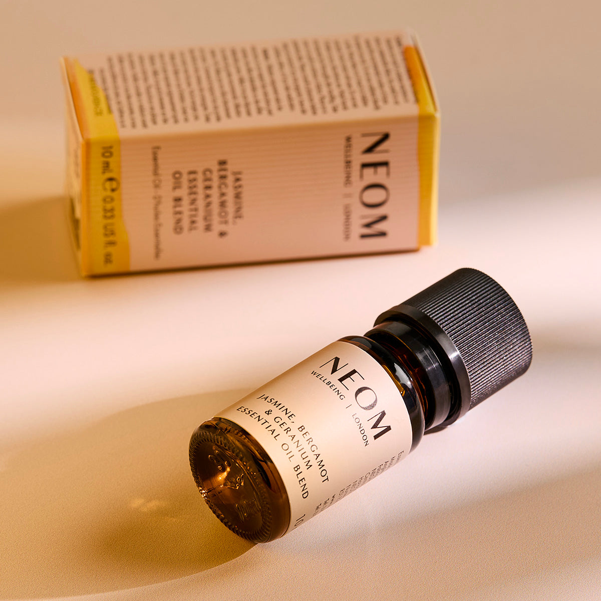 NEOM essential oil bottle and box on a beige background