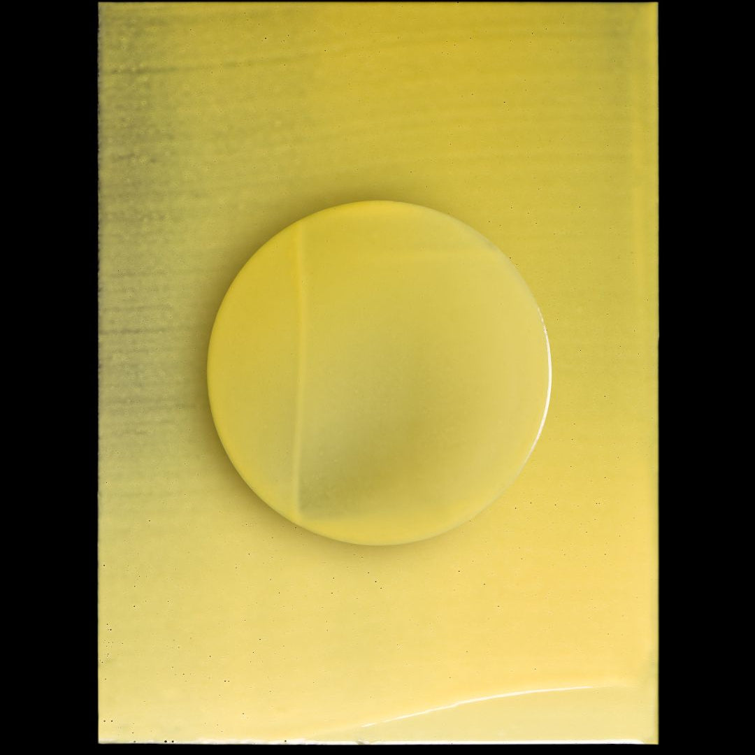 A translucent yellow circular gel or liquid drop centered on a square yellow sample card, photographed against a black background.