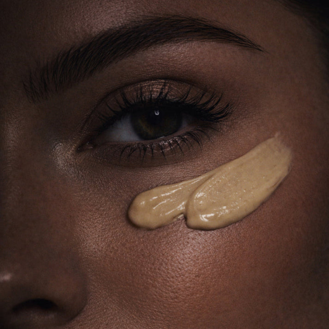 Close-up of a woman's face with two beige makeup swatches on her cheek.