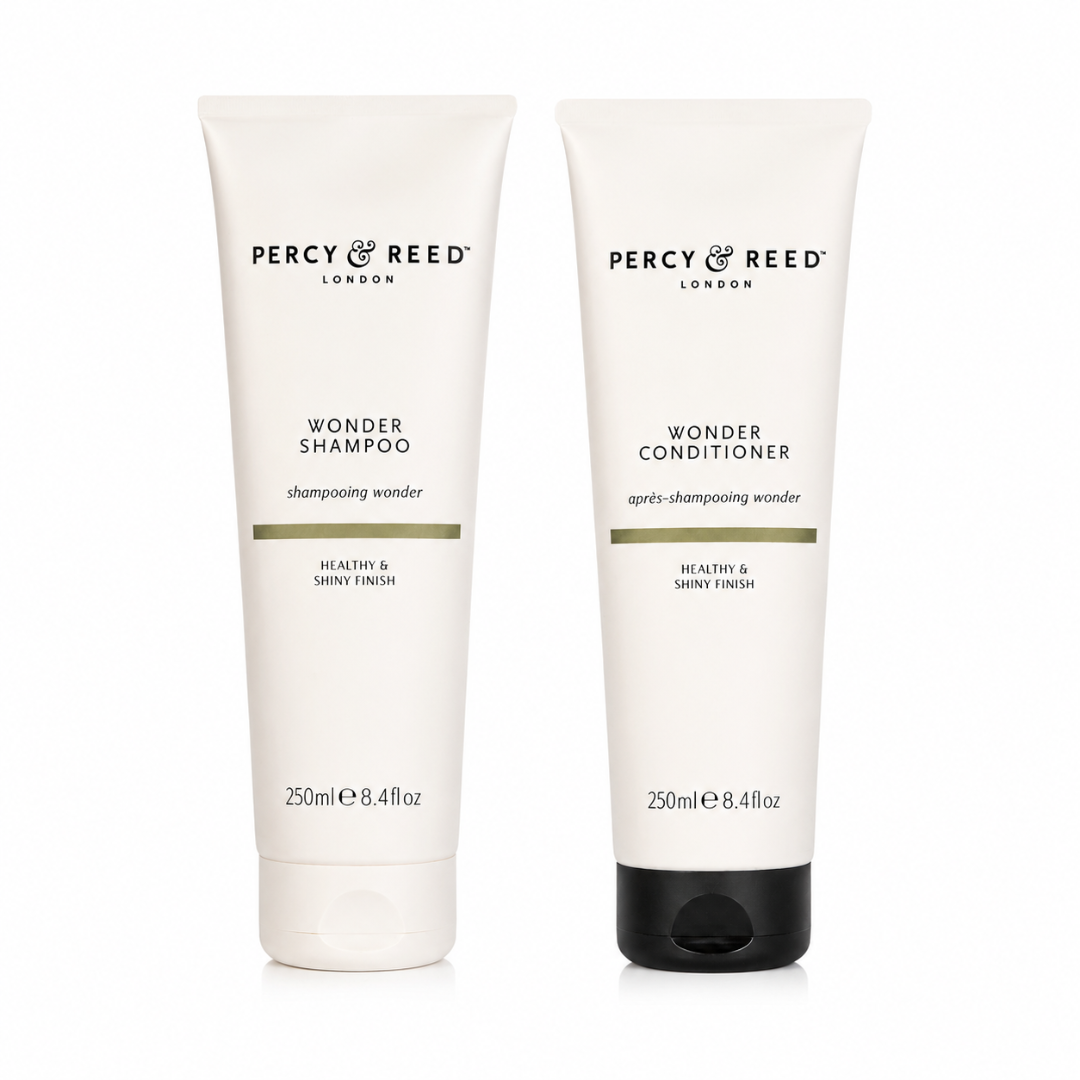 Two white Percy & Reed London tubes, Wonder Shampoo and Wonder Conditioner, standing side by side on a white background.