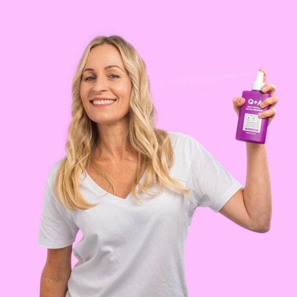 Woman holding a purple bottle with a Q+A logo against a pink background