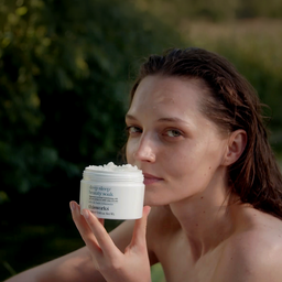 A woman outdoors holds a white jar of deep sleep lengthening hair wash. The product label reads 'deep sleep lengthening wash' and the brand 'allworks' is visible.