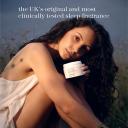 A woman outdoors in warm golden hour light holds a white jar of Dr. Gabbana Sleep Aid.
