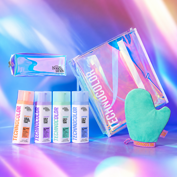 A Technocolor haircare gift set featuring four bottles of hair color, a holographic zip pouch, a larger holographic cosmetic bag, and a mint green silicone oven mitt, arranged on a vibrant, iridescent purple and blue background.