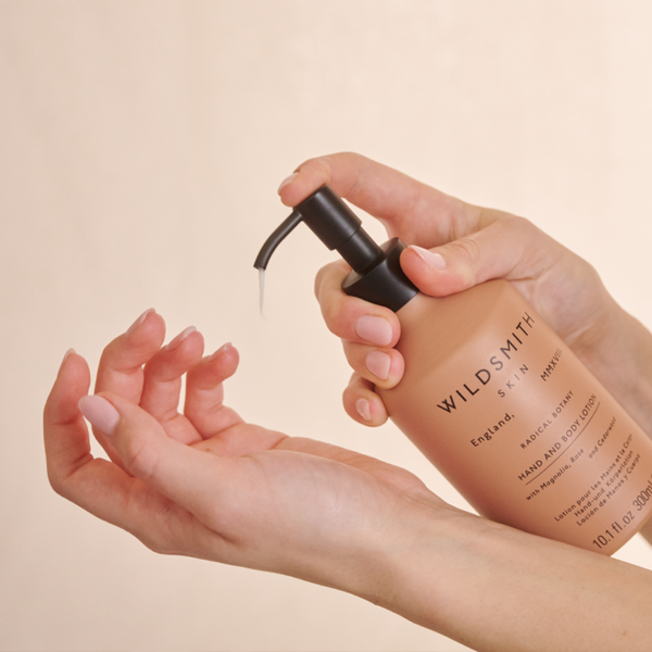 Hand holding a Wildsmith skin care product with a beige background