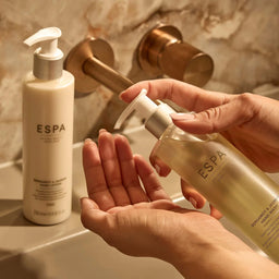 Person holding a bottle of ESPA hand wash with another bottle in the background.