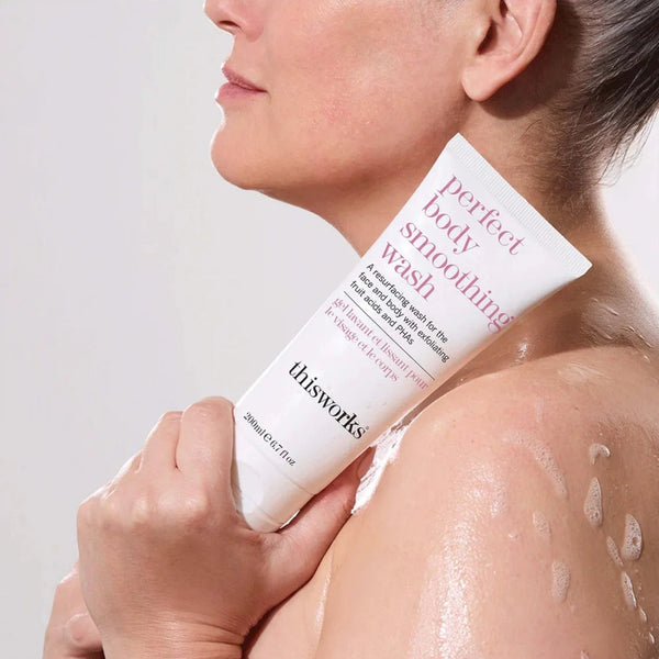 Person holding a tube of 'this works' perfect body wash on a plain background