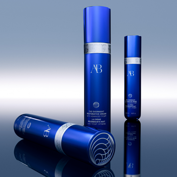 Three blue skincare bottles with 'AB' branding on a reflective surface.