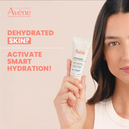 Woman holding Avene hydrating cream with promotional text on a beige background