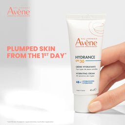 Avené Hydrance cream tube held by a hand with brand logo and text on a light gray background
