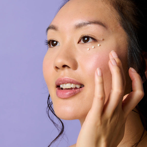 Model dotting the retinol eye cream around her eyes with her finger